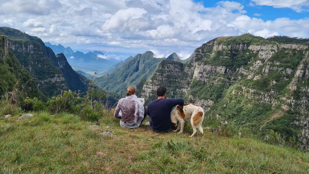 Casal sentado na borda do cânion com um cachorro